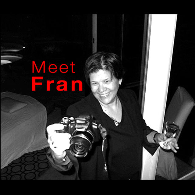 Photo of artist, Fran Lamothe taking a photograph with her camera in her hand.